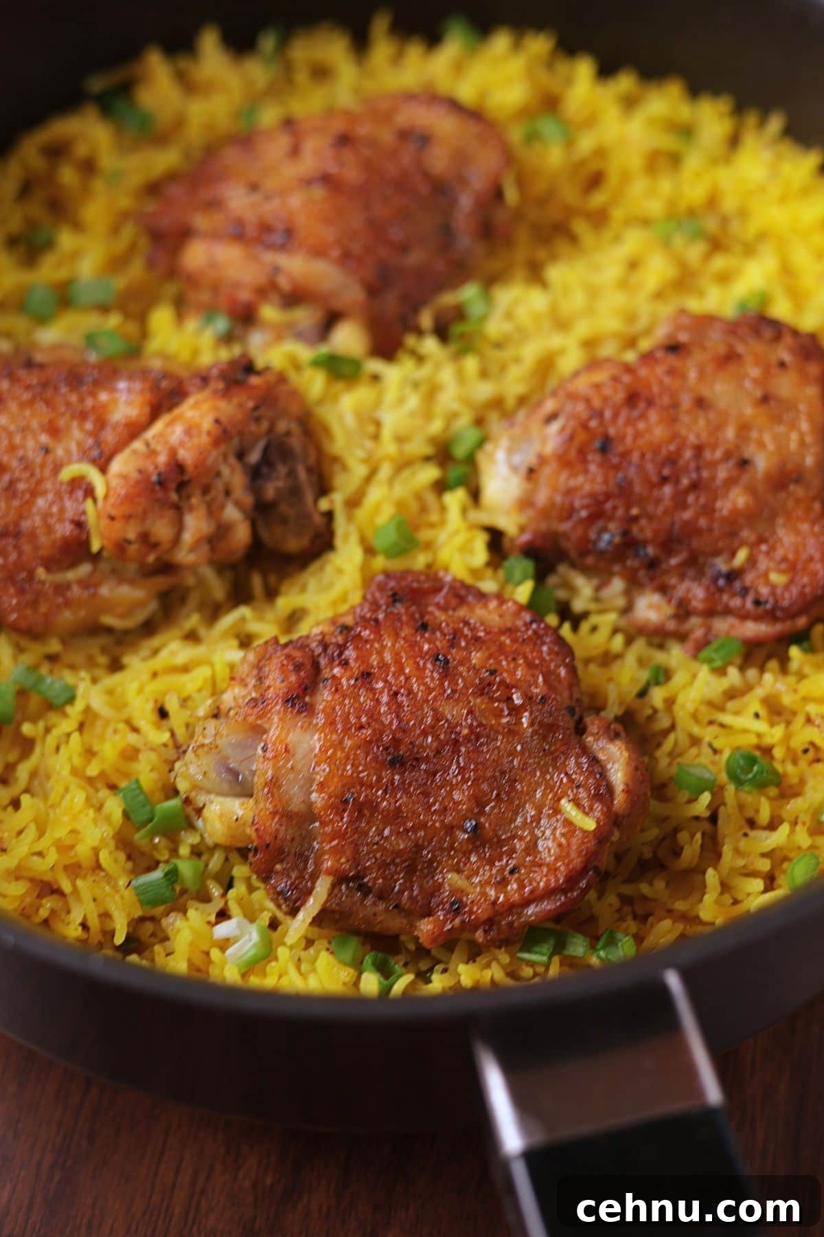 Chicken and yellow rice with four chicken thighs in a pan.