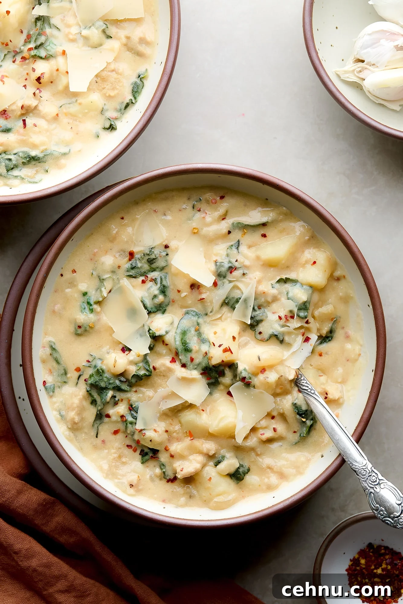 bowl of creamy vegan zuppa toscana with vegan parmesan on top