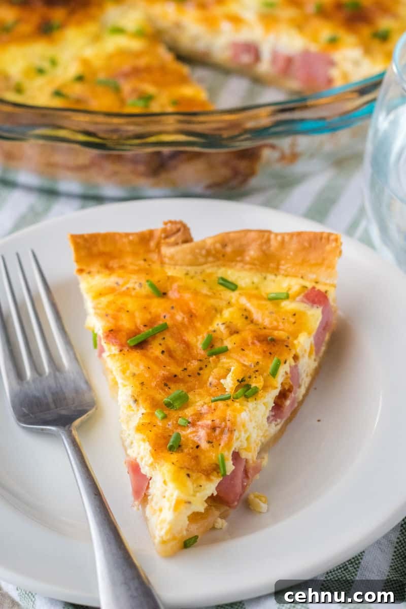 Brunch is a snap when you make this Easy Ham and Cheese Quiche! Simply prep your pie crust, pour in the filling and bake. It's practically fool-proof! slce of quiche on a plate with a fork