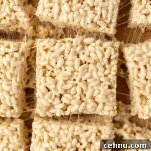 Gluten-Free Rice Krispie Treats Recipe 13 Rice cereal treats sliced into squares, resting on top of parchment paper.