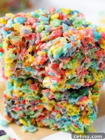 Two cereal treats stacked , made with Fruity Pebbles.