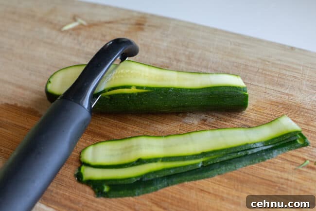 Peeling zucchini into ribbons with a vegetable peeler.