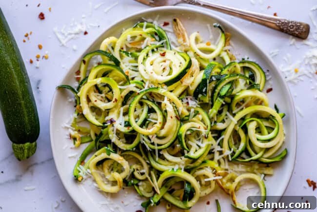 Zucchini noodles on a white plate with a fork.