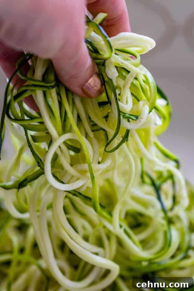 Hand lifting zoodles off a countertop.