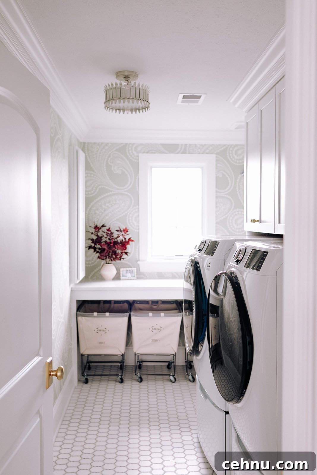 Stunning laundry room with white washer and dryer, pink plant and light green wallpaper.