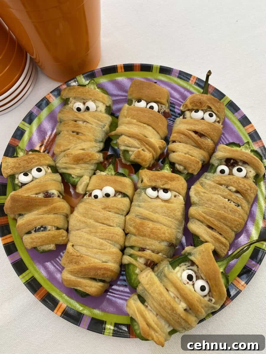 Bacon Wrapped Jalapeno Popper Mummies 4 A plate with eight wrapped jalapeño poppers wrapped in dough.