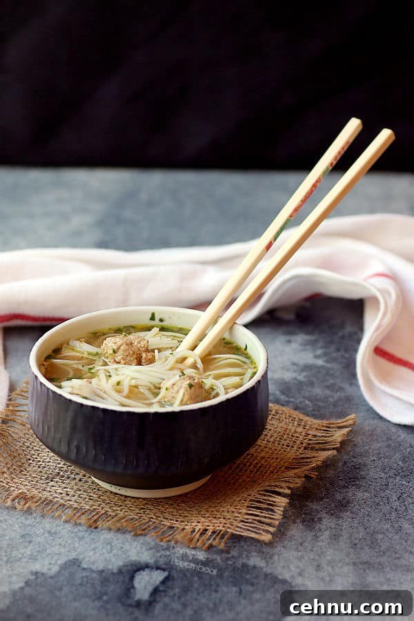 Chopsticks in a bowl of rice noodle soup with turkey meatballs