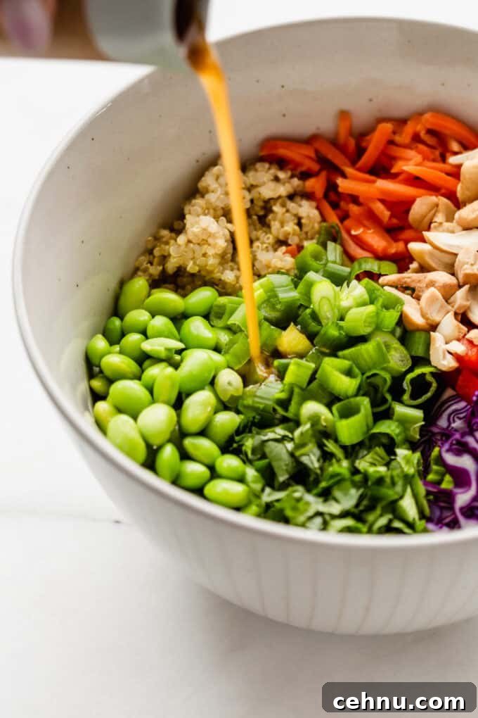 edamame salad in a large bowl with sesame dressing being poured into it