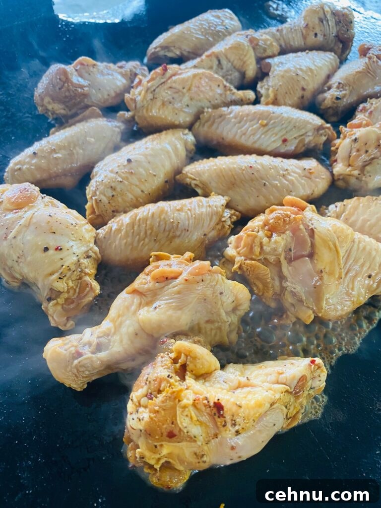 Griddle-Crisped Lemon Pepper Chicken Wings 4 seasoned wings cooking on the griddle