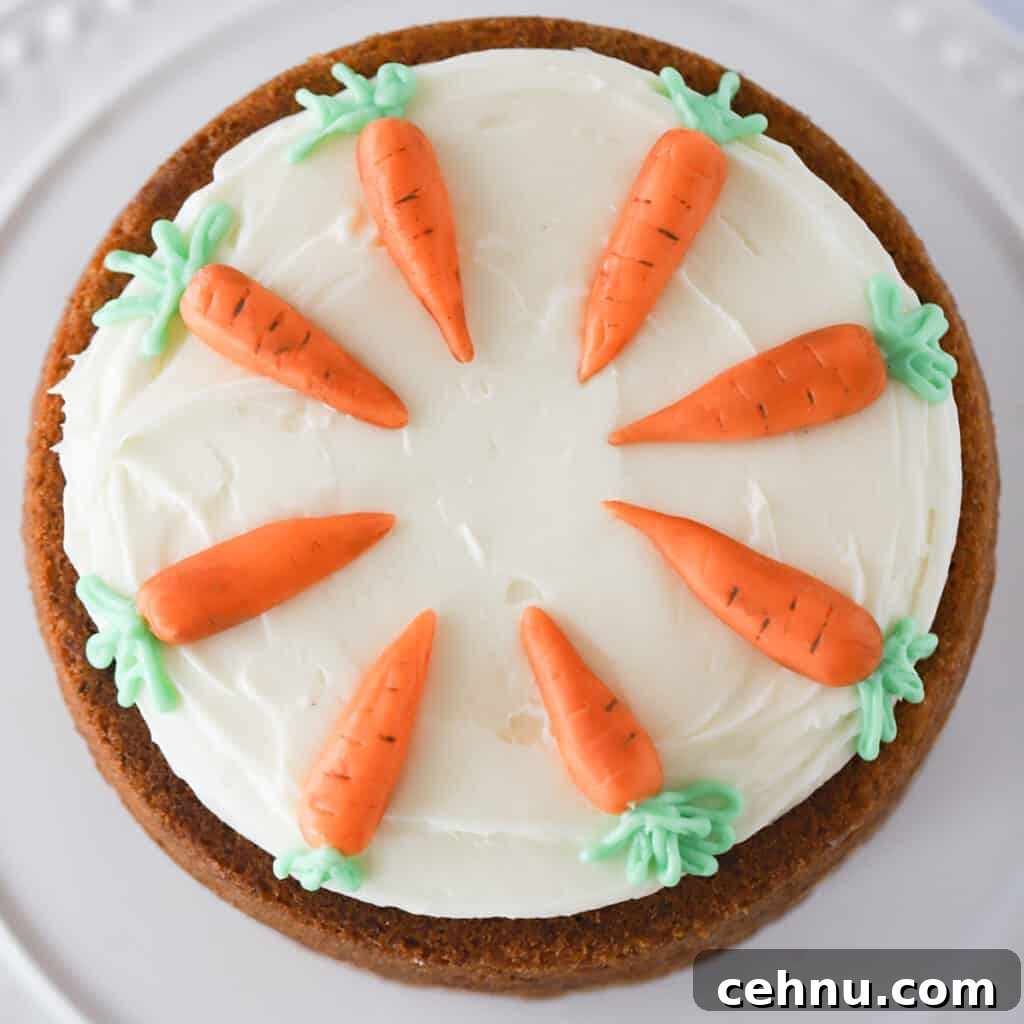 Photo of a decorated carrot cake from above, frosted with cream cheese frosting and carrot decorations.