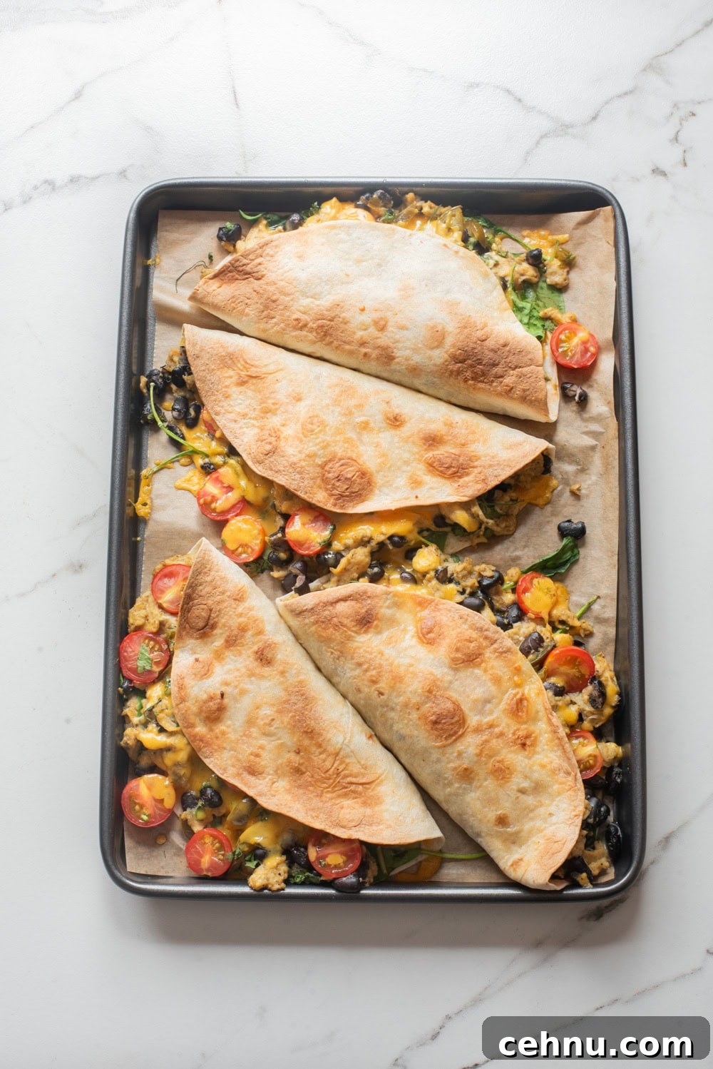 An overhead image of baked breakfast quesadilla on a sheet pan.
