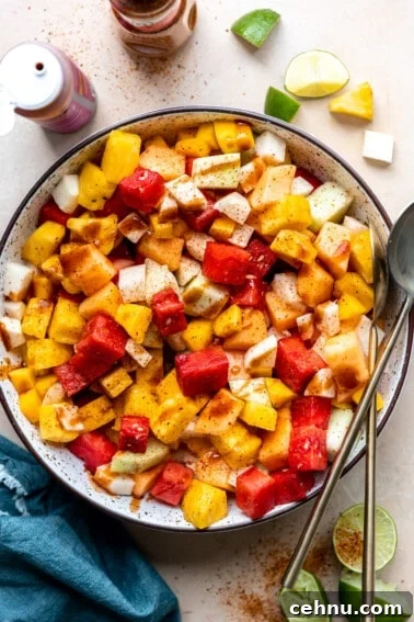 Tajin Seasoning: What It Is and How to Use It 6 Bowl filled with mexican fruits, topped with tajin and drizzled with chamoy.