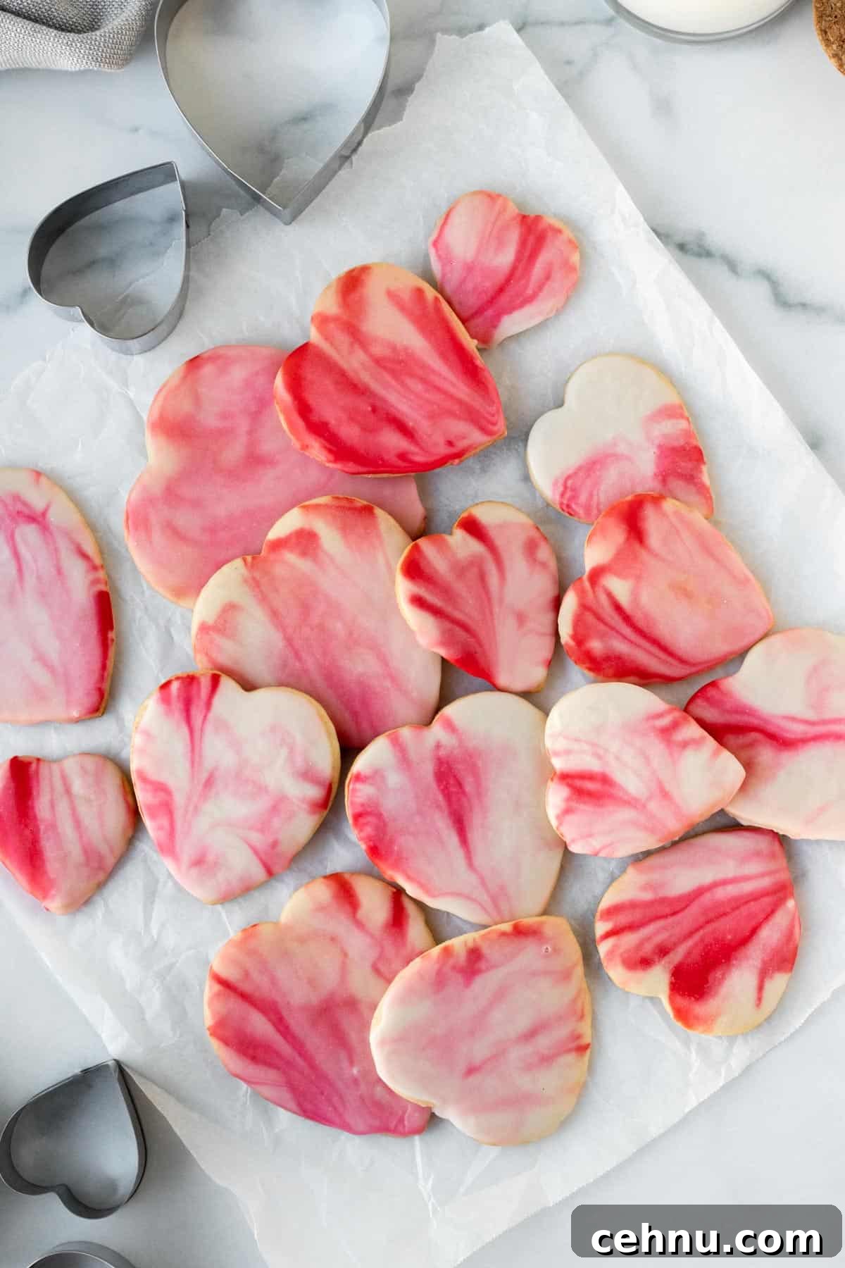 Marbled Sugar Cookie Recipe with Decorating Tips 2 pile of red and pink marbled heart shaped sugar cookies on white parchment paper