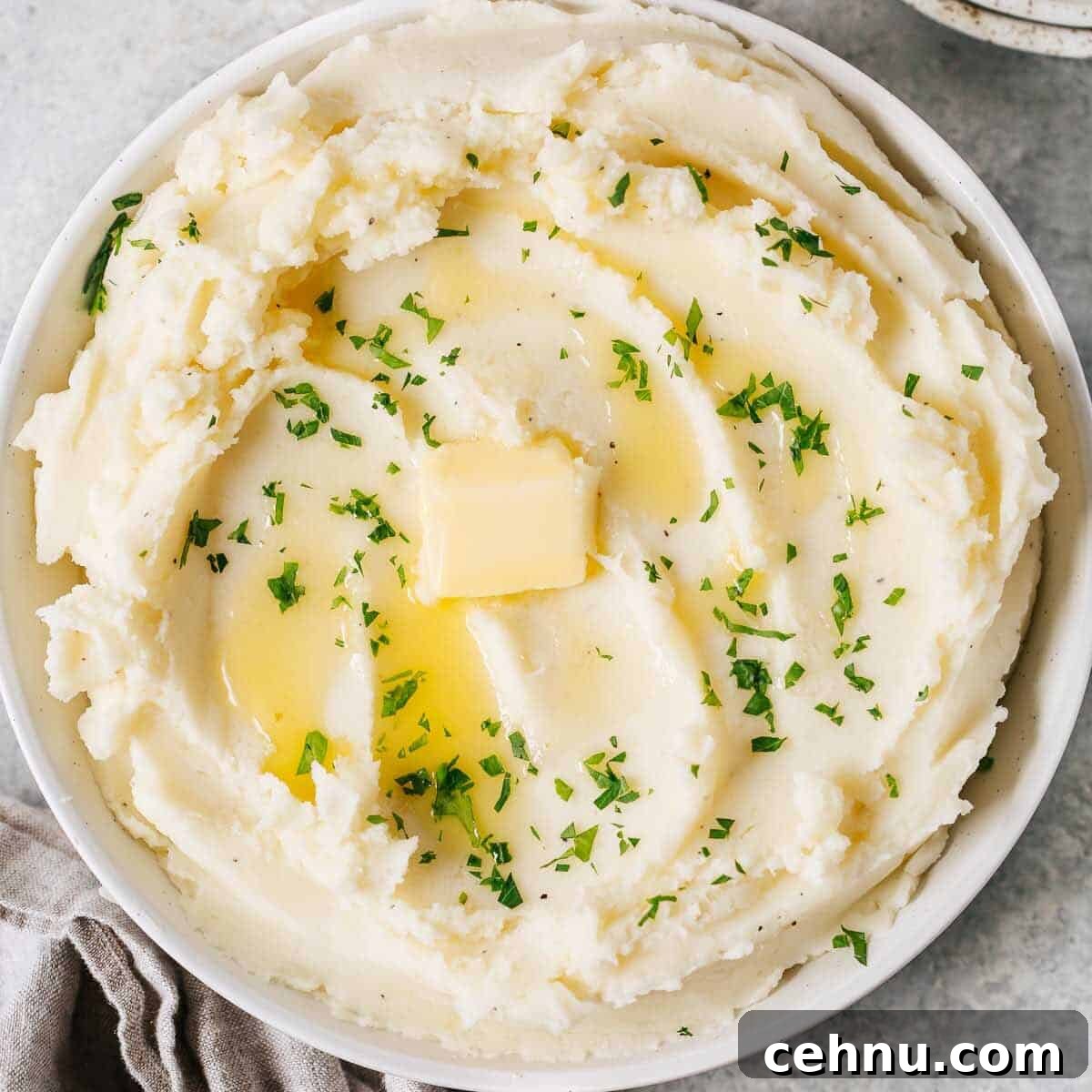 Easter Menu Ideas: Brunch, Dinner and Dessert Recipes 18 overhead view of a creamy mashed potatoes in a white bowl with butter on top.