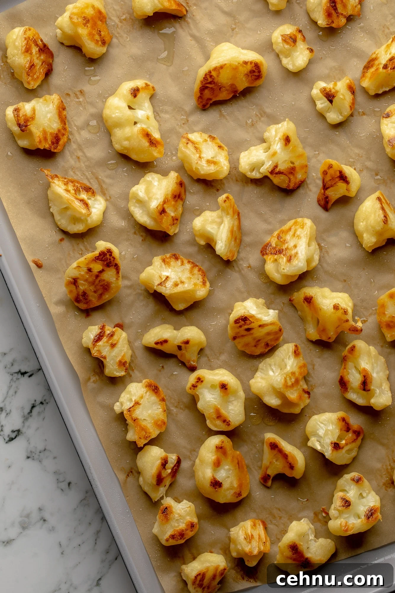 Overhead view of battered and baked cauliflower florets on a baking sheet.