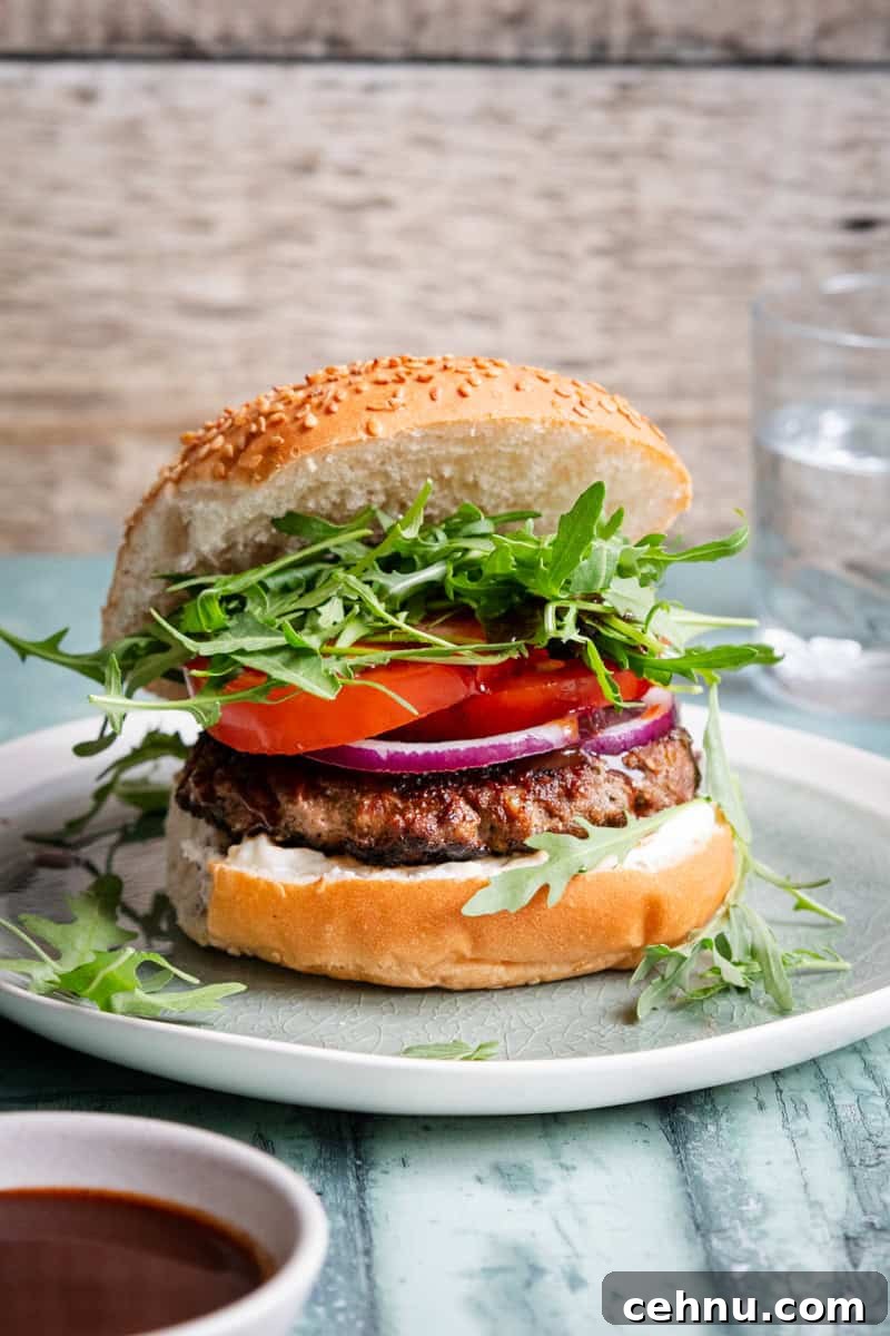 lamb burger in a bun next to a bowl of bbq sauce
