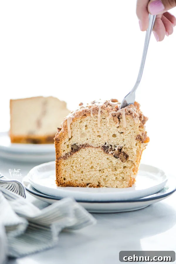 a slice of gluten free sour cream coffee cake on a plate with a fork taking a piece out