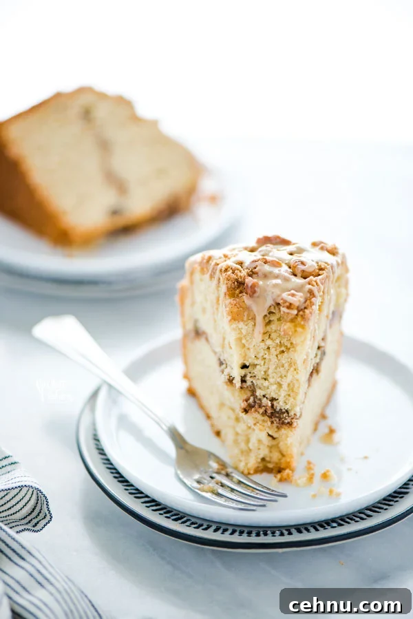 a slice of gluten free sour cream coffee cake on a white plate with a fork that has a bite taken out