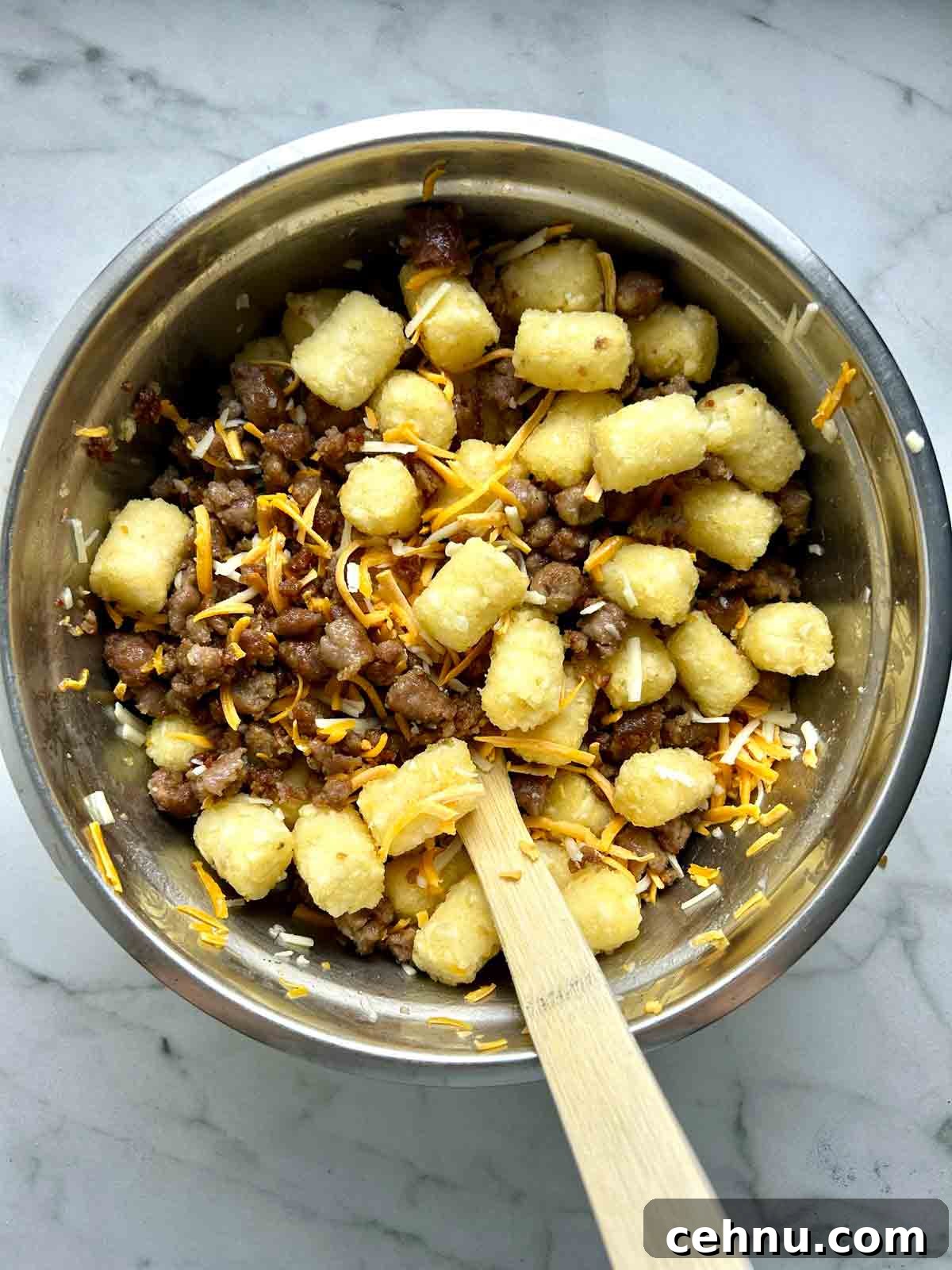 Cheesy Sausage and Tater Tot Breakfast Casserole Recipe 5 tater tots, breakfast sausages, and cheeses tossed in bowl.