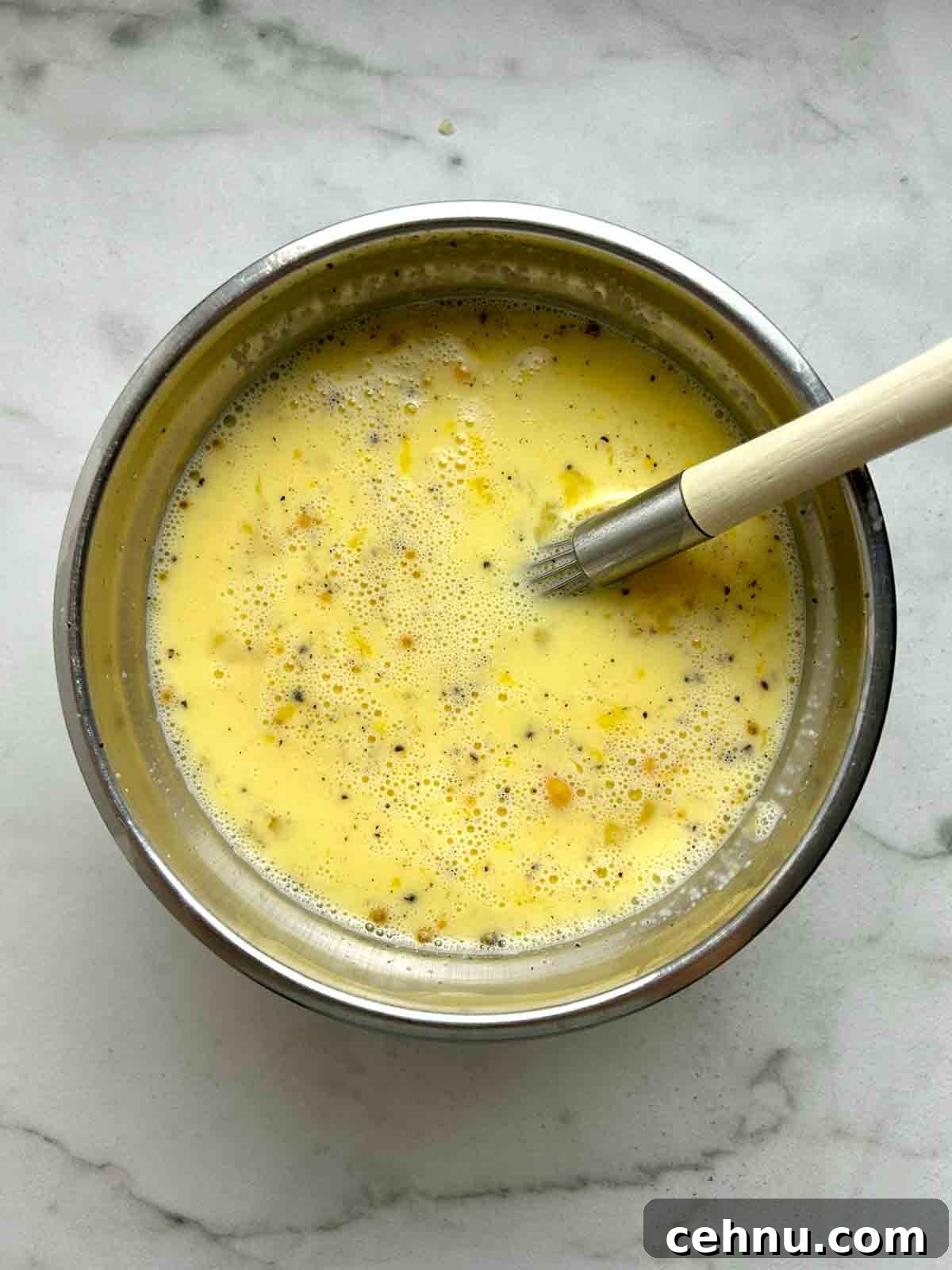 Cheesy Sausage and Tater Tot Breakfast Casserole Recipe 7 egg and milk mixture whisked in bowl.