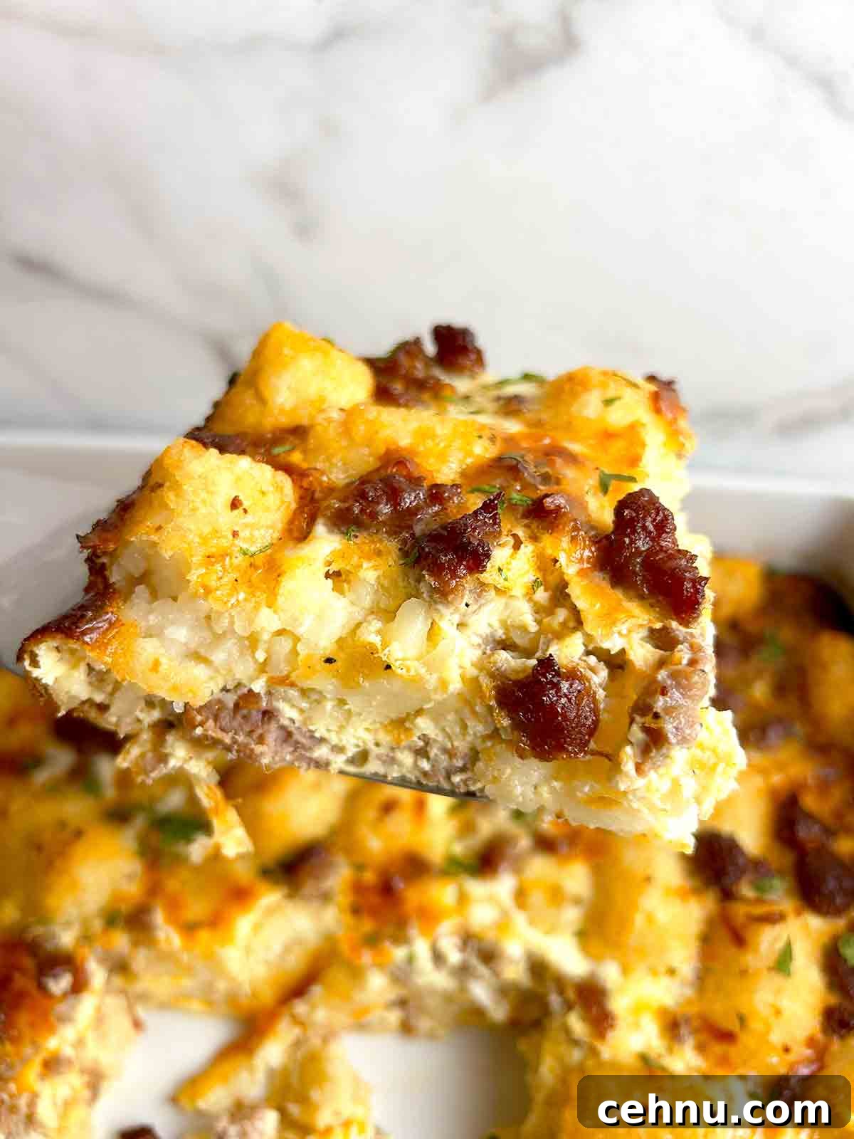 Cheesy Sausage and Tater Tot Breakfast Casserole Recipe 10 spatula lifting slice of casserole.