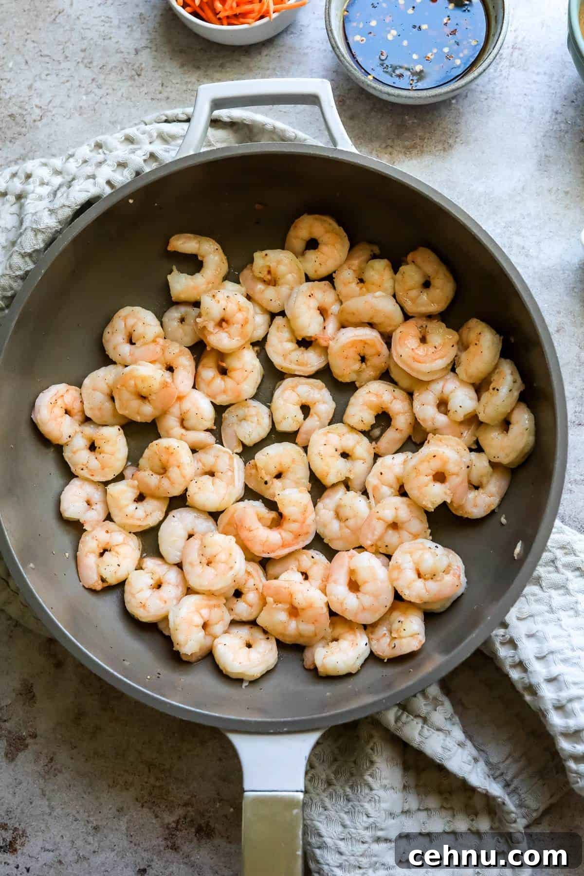 Grey skillet with cooked shrimp in it.