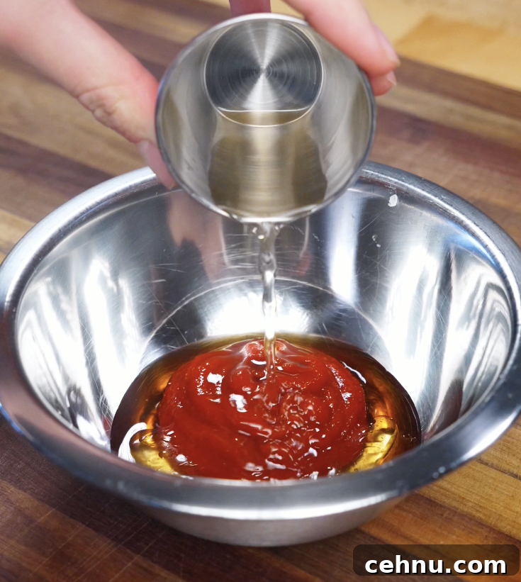 Gochujang sauce being mixed in a stainless steel bowl with sesame oil, rice vinegar, garlic, and sugar to create a bold bibimbap sauce.