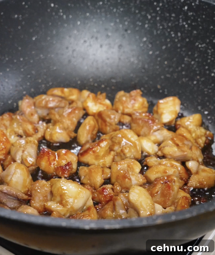 Bite-sized pieces of marinated chicken thighs cooking in a pan until lightly caramelized and golden brown for chicken bibimbap.