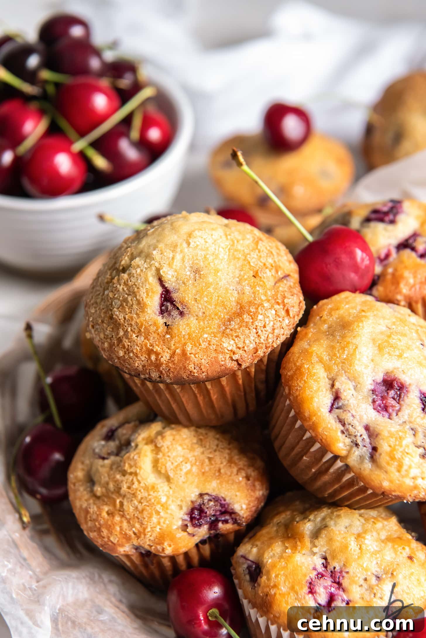 Cherry Almond Muffins with Almond Extract 2 cherry muffins in a pile in front of bowl of fresh cherries