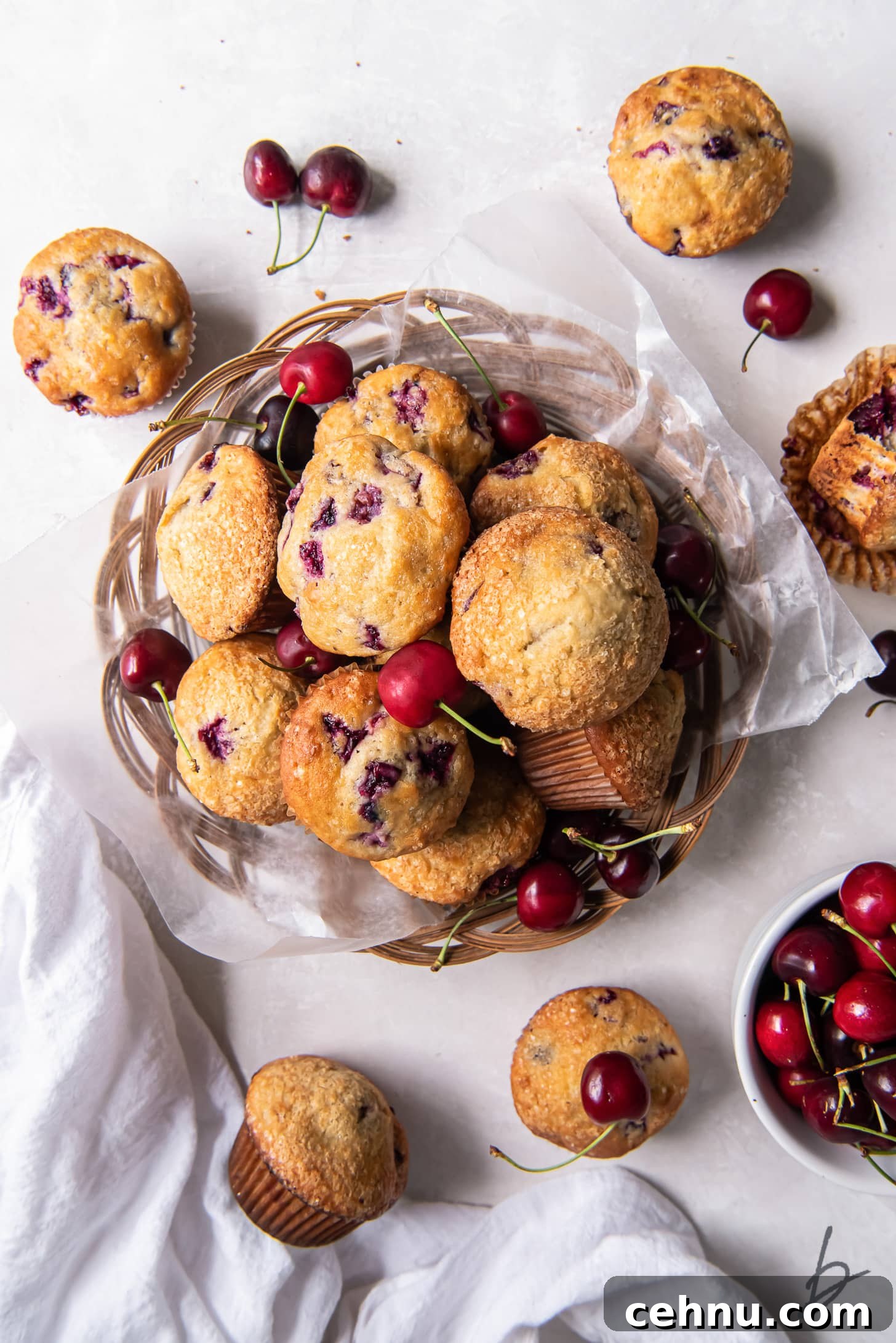 Cherry Almond Muffins with Almond Extract 5 pile of cherry muffins on parchment paper in a basket next to a few more muffins