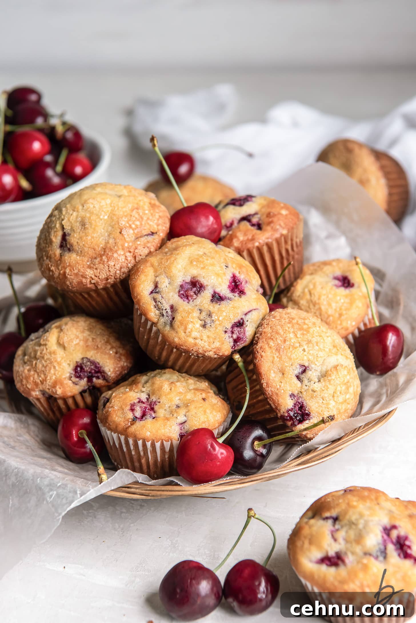 Cherry Almond Muffins with Almond Extract 6 pile of cherry muffins with a few fresh cherries on a shallow basket
