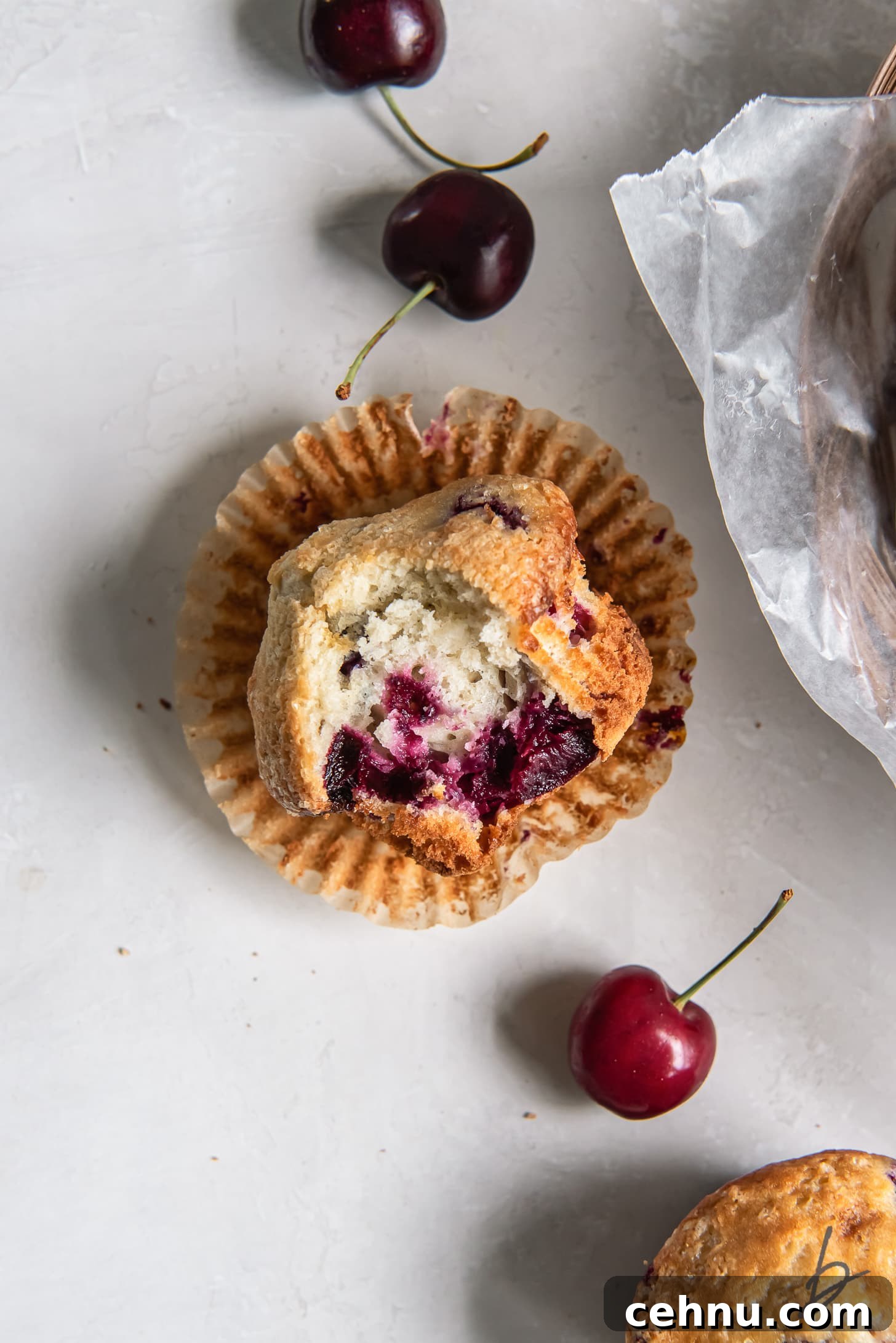 Cherry Almond Muffins with Almond Extract 7 cherry muffin with a bite laying on its side on open paper muffin liner