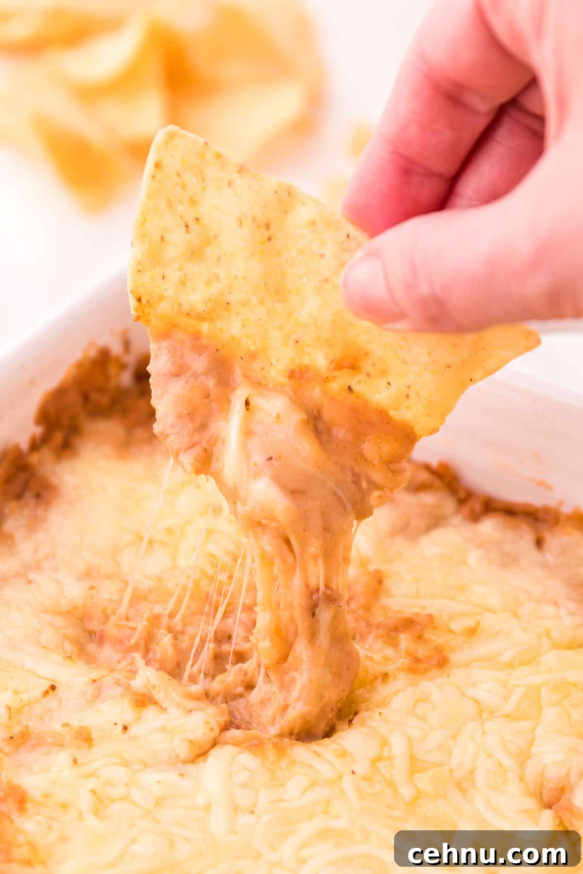 dipping a tortilla chip into bean dip