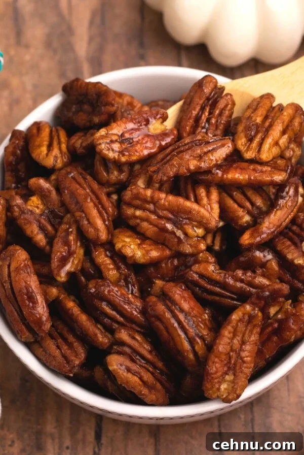 Air Fryer Mummy Hot Dogs: Halloween Appetizer Recipe 13 Juicy brown pecans in a white bowl after being cooked in the air fryer with scattered pecans on a wooden table