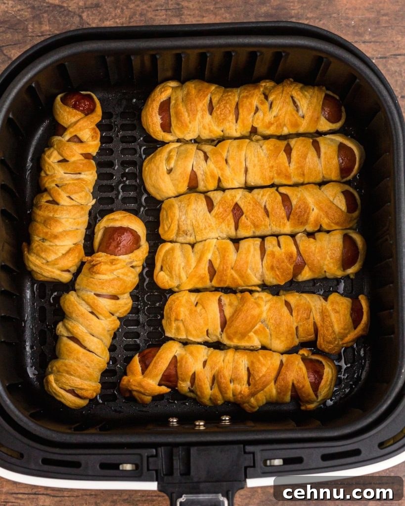 Air Fryer Mummy Hot Dogs: Halloween Appetizer Recipe 7 Air fryer basket full of mummy dogs after being cooked in the air fryer.