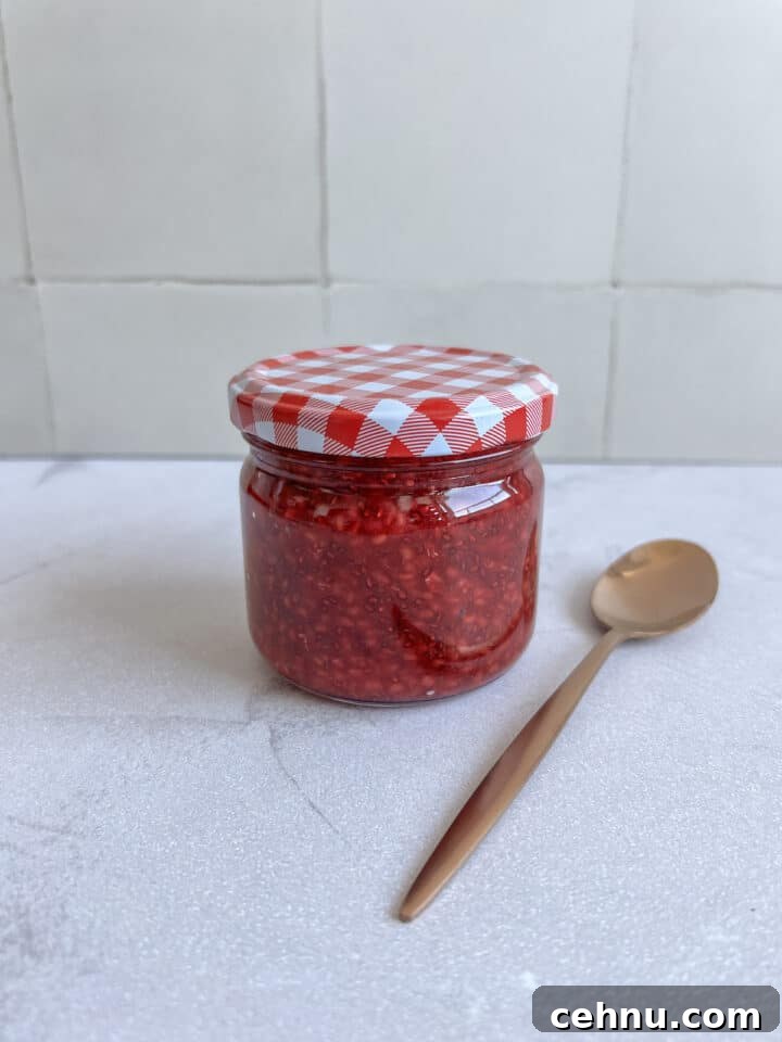 jar of chia jam with a red checkered lid and a gold spoon resting beside it