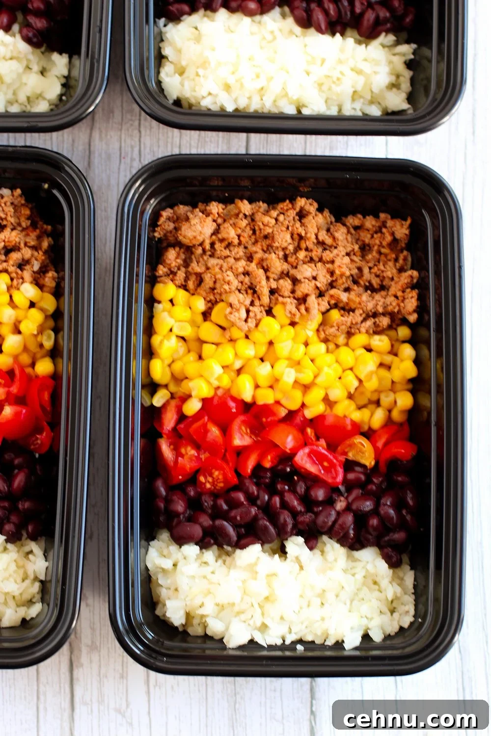 add corn and tomatoes to meal prep containers with meat and cauliflower rice