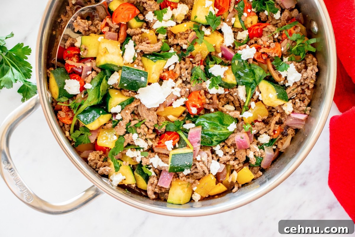 10 Ground Beef Recipes for Quick Weeknight Dinners 2 A skillet filled with cooked ground beef, zucchini, tomatoes, spinach, and crumbled feta cheese, garnished with parsley.