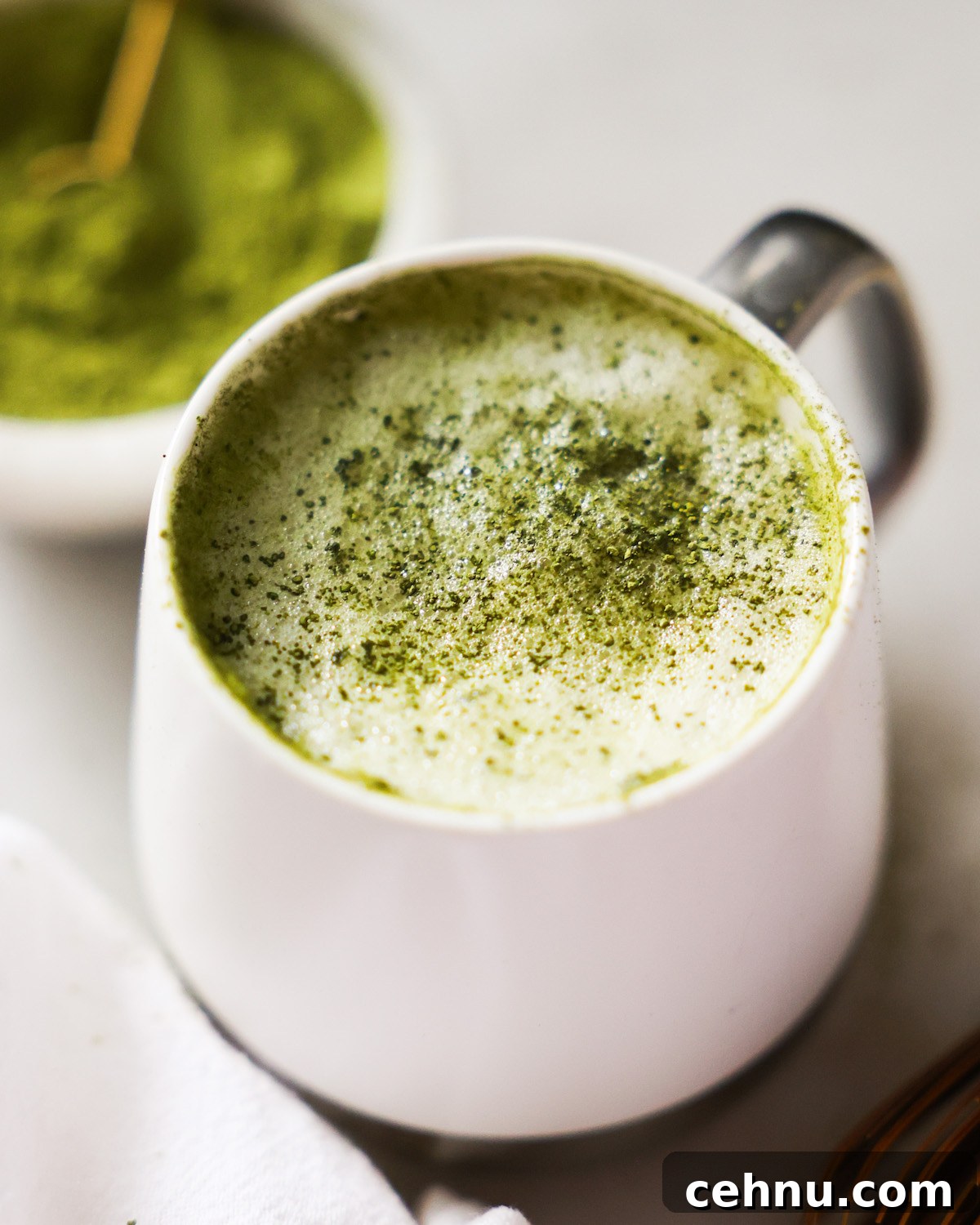 A close-up image of a mug of oat milk latte on the counter with a towel.