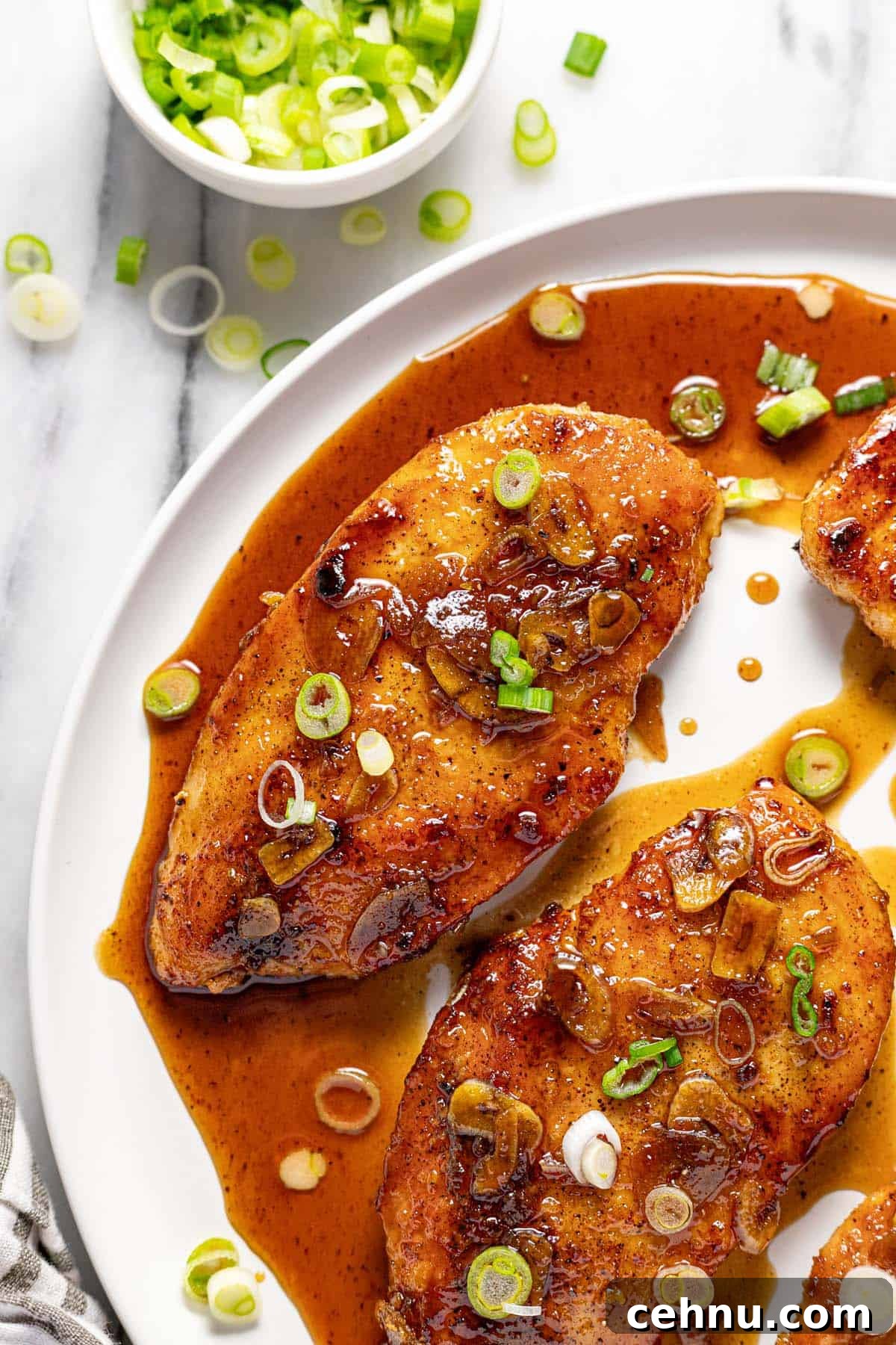 20-Minute Honey Garlic Chicken 8 Close up of a large round plate with honey garlic chicken garnished with sliced green onion.