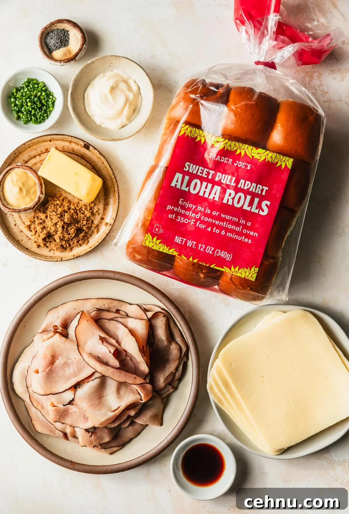 Oven-Baked Brown Sugar Ham and Melted Cheese Sliders 3 Brown and white bowls of ham, cheese, Worcestershire, brown sugar, butter, mustard, mayo, chives, and spices next to Hawaiian rolls on a tan counter.