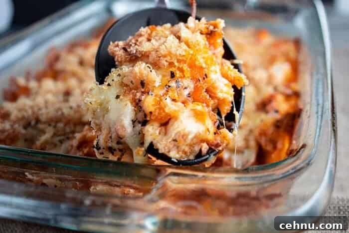 sideview of keto chicken parmesan casserole in glass dish with black serving spoon scooping a serving