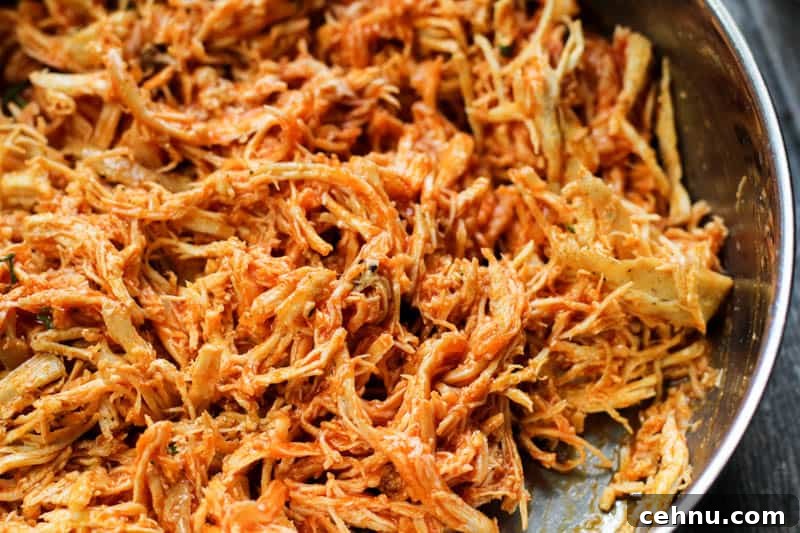 shredded chicken covered in buffalo sauce in a pan