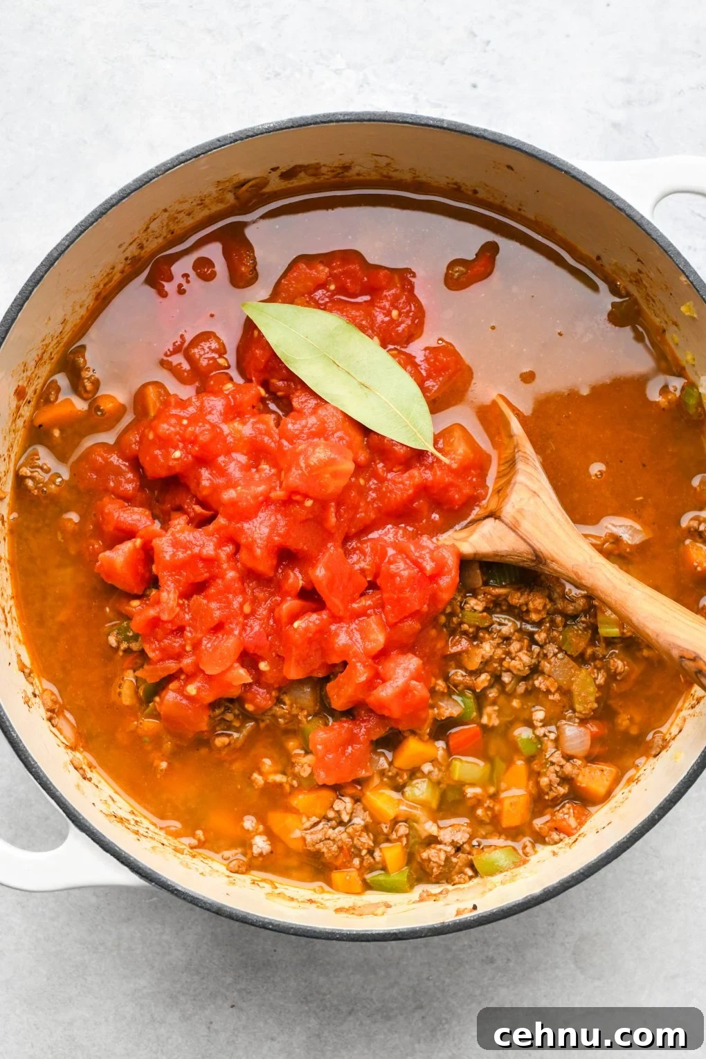 Broth, diced tomatoes, and bay leaf added to the large soup pot.