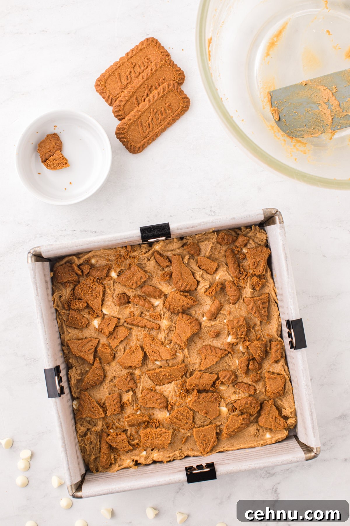 Topping a pan of blondies with biscoff cookies.