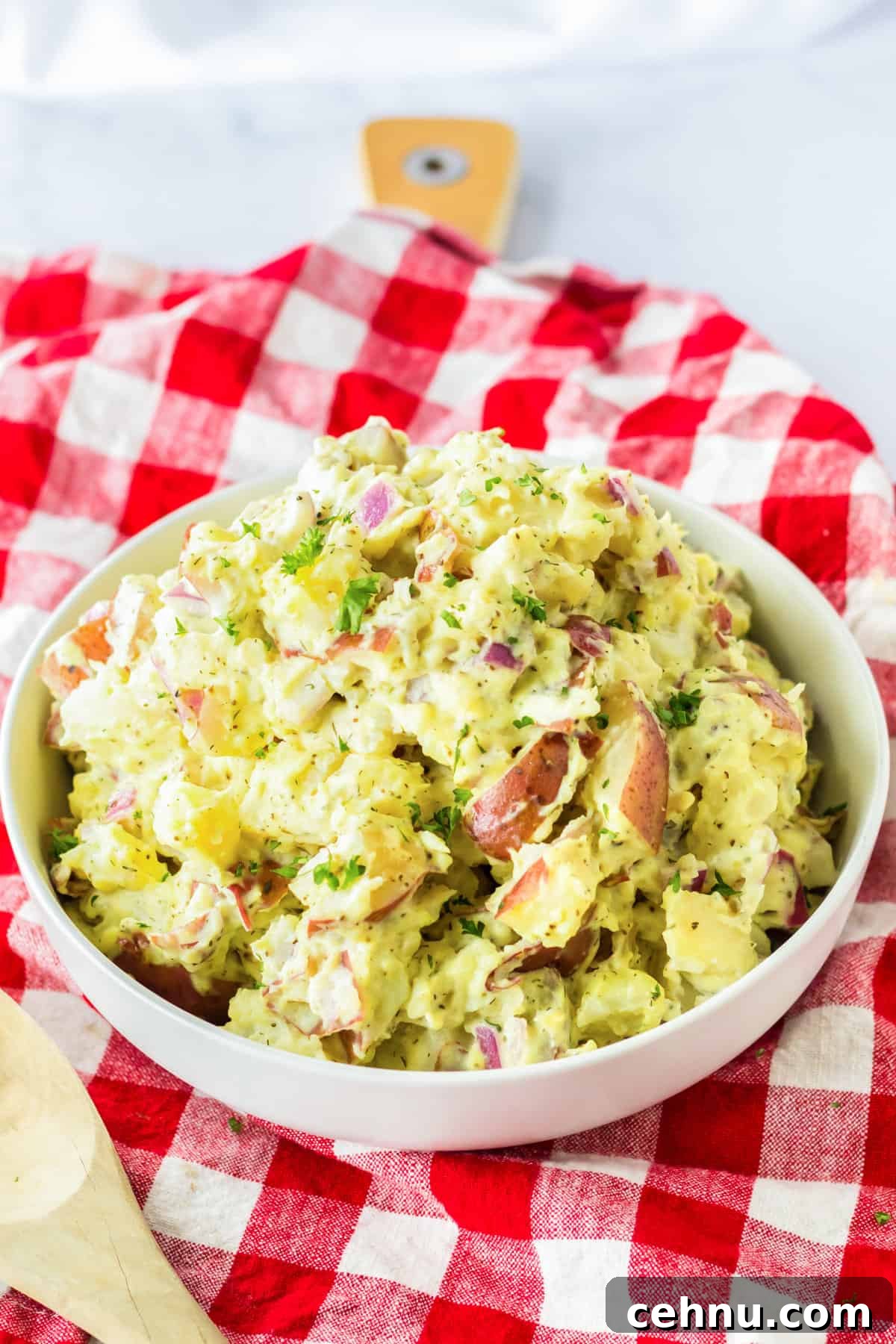 Bowl of red skinned potato salad on a red plaid linen.