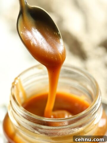 Thick caramel sauce dripping from a spoon over a jar