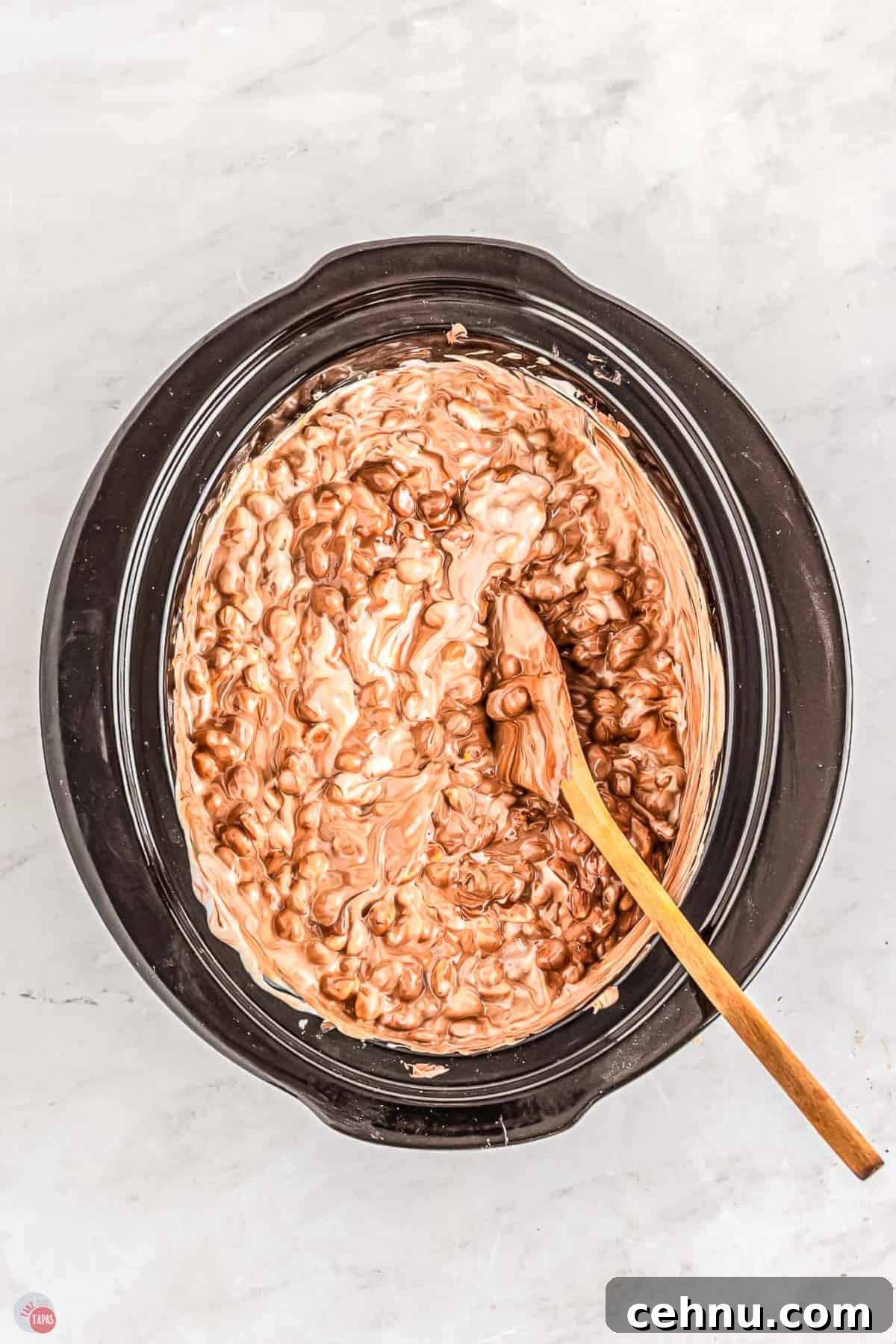 Slow Cooker Peanut Clusters: No-Bake Candy Recipe 6 wood spoon stirring chocolate in a slow cooker pot