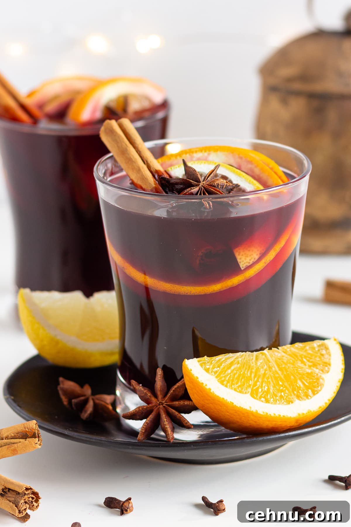 Glühwein: Traditional German Mulled Wine Recipe 3 Two glasses of German Gluhwein with Christmas bell and lights in the background.