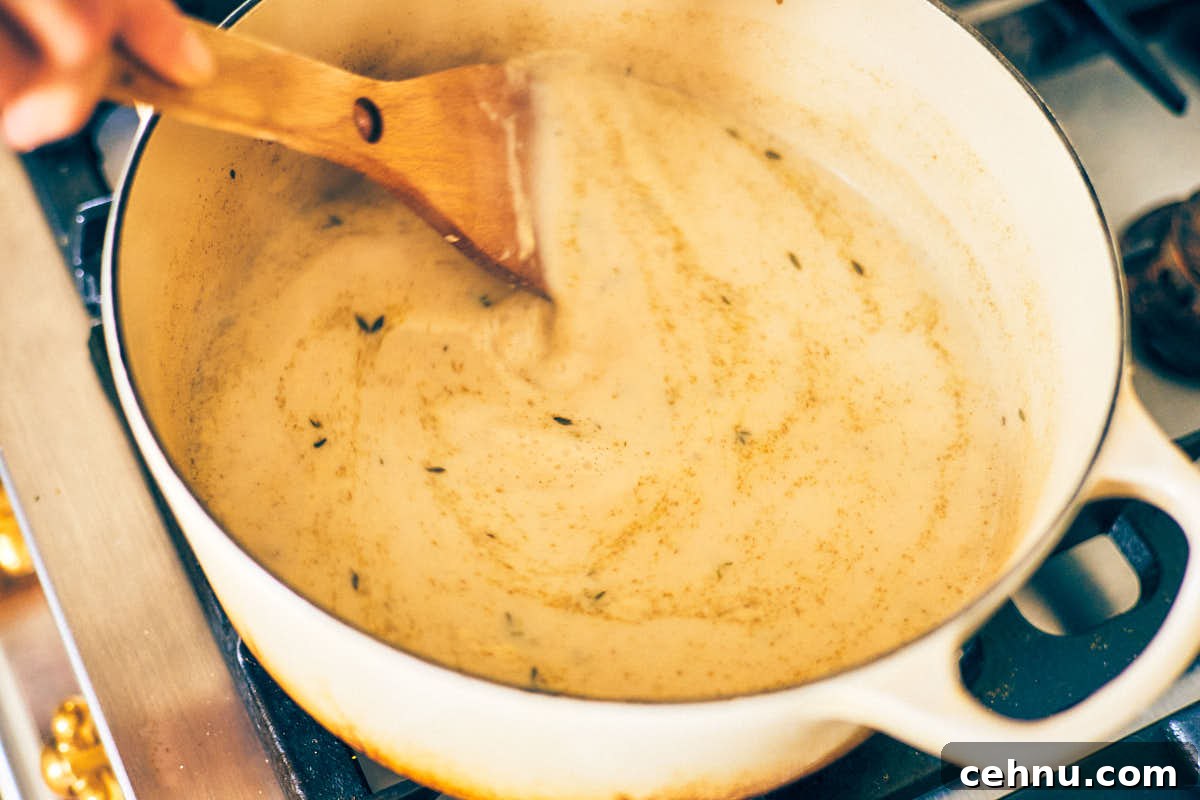 Garlic herb pasta sauce being stirred in a pot.